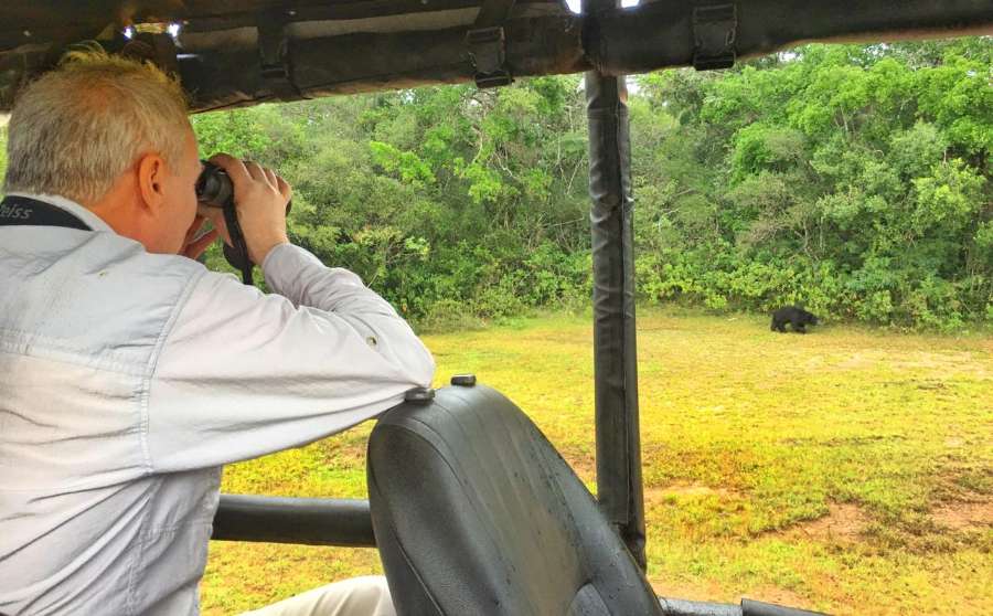 A Wilpattu safari guest is taking a picture if a Sloth Bear